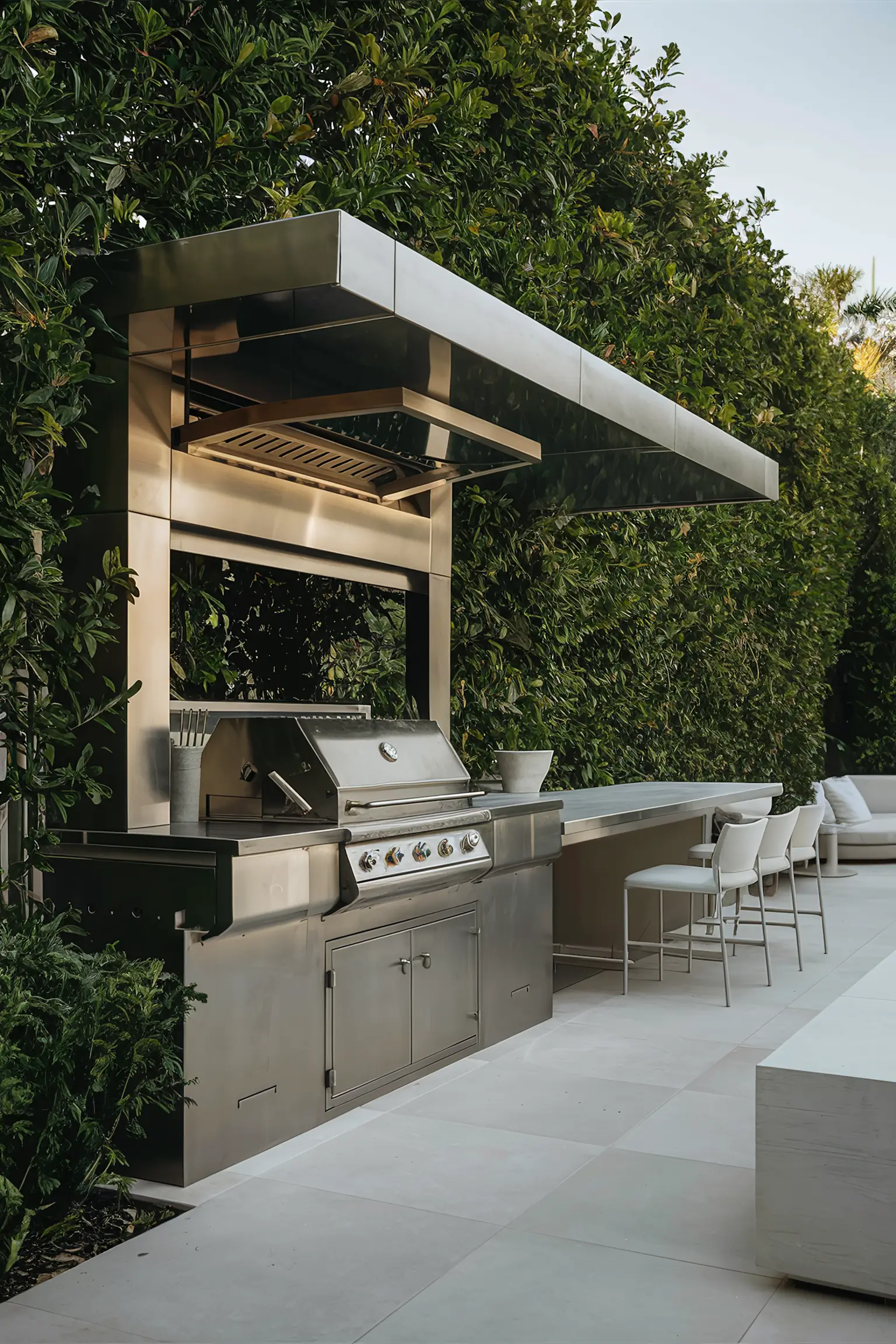 Modern outdoor grill station surrounded by greenery.