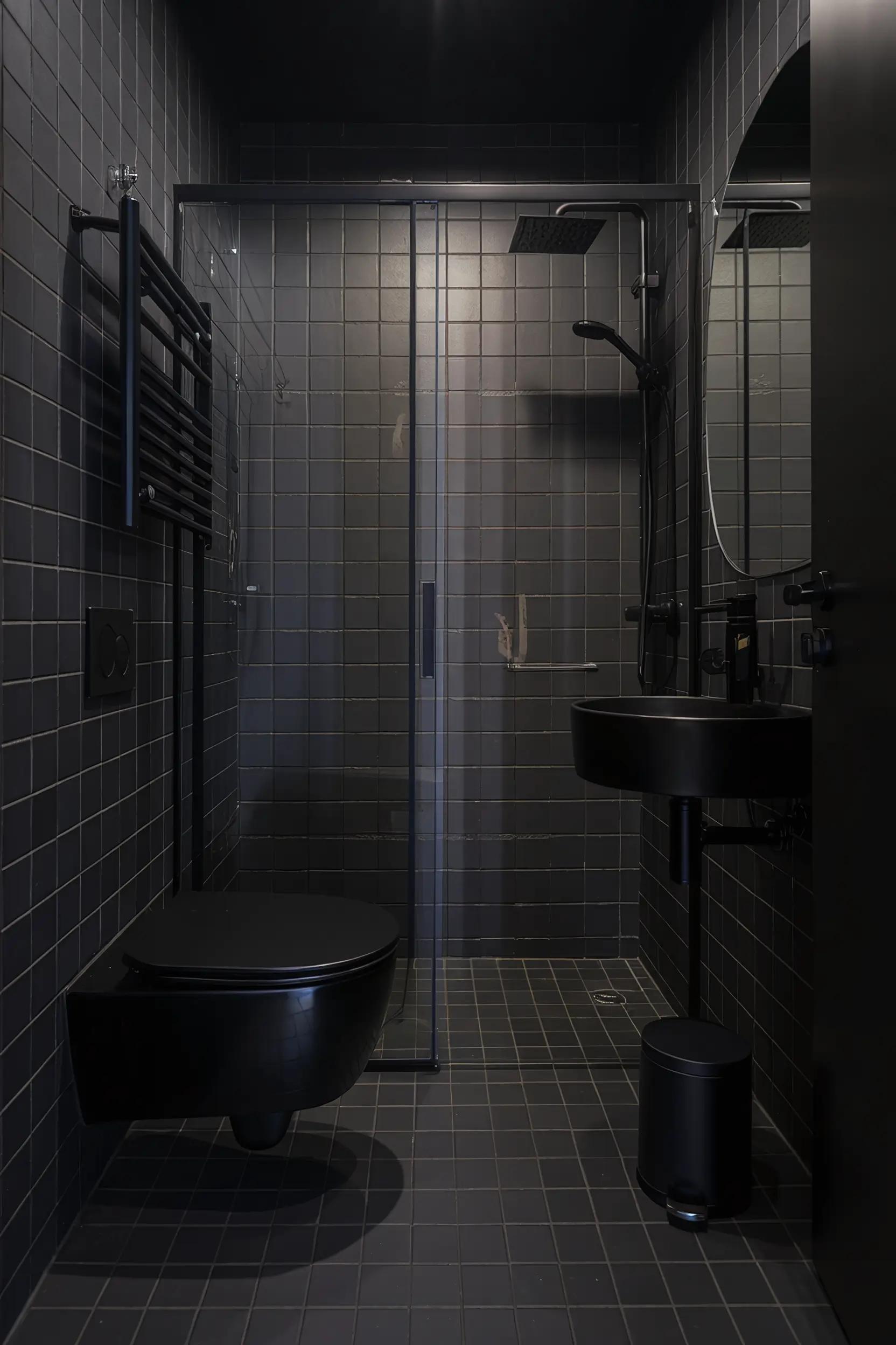 Small luxury bathroom with an all-black theme, black tiles, and sleek fixtures.