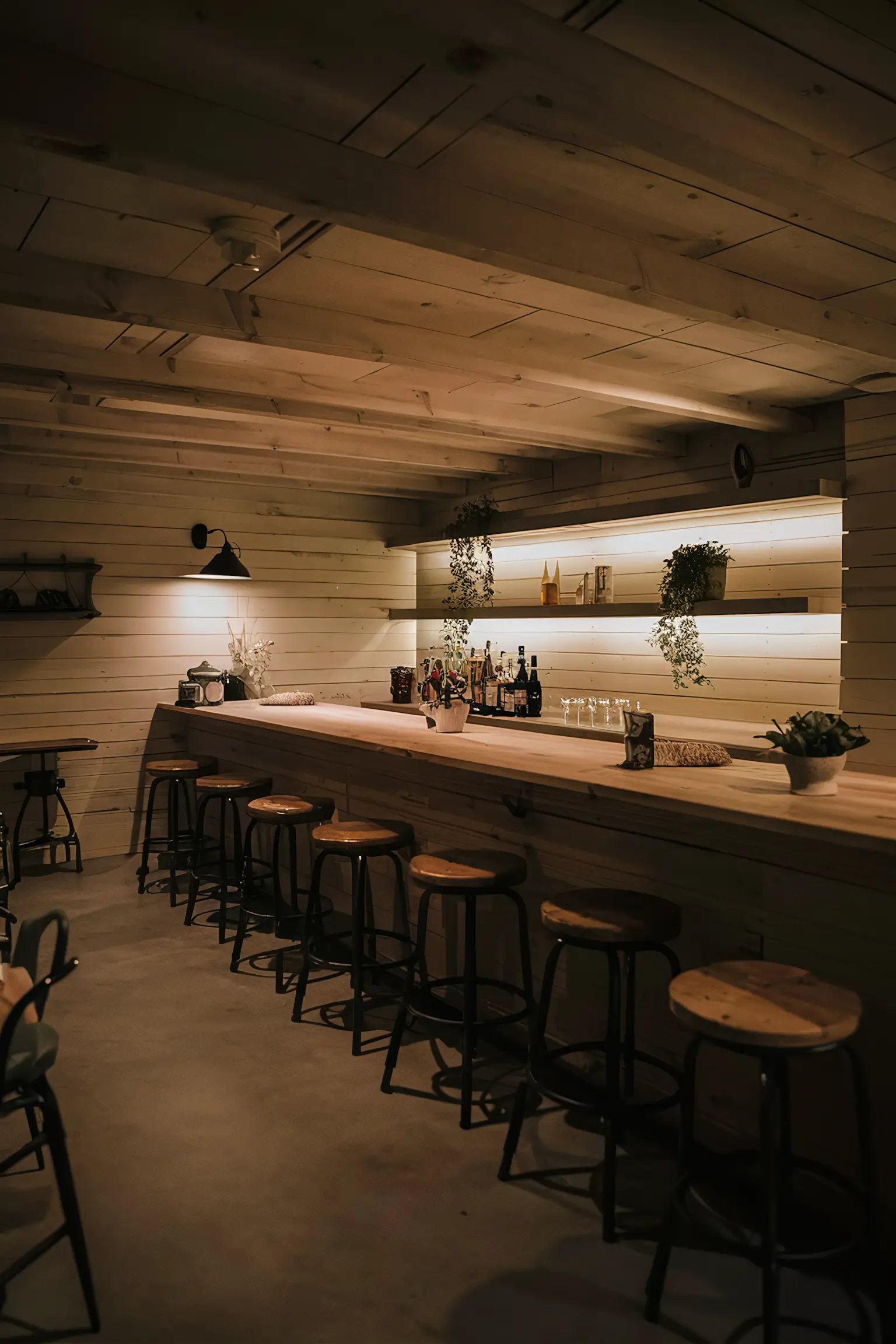 Farmhouse-style basement bar with shiplap walls and rustic decor.